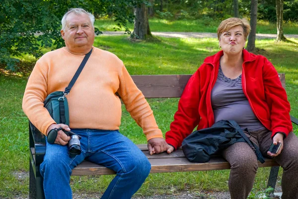 Сімейна зріла пара відпочиває на лавці і фотографується — стокове фото