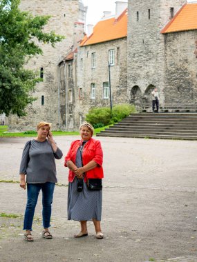 İki olgun tombul kadın eski kasabada dolaşıp fotoğraf çekiyor.