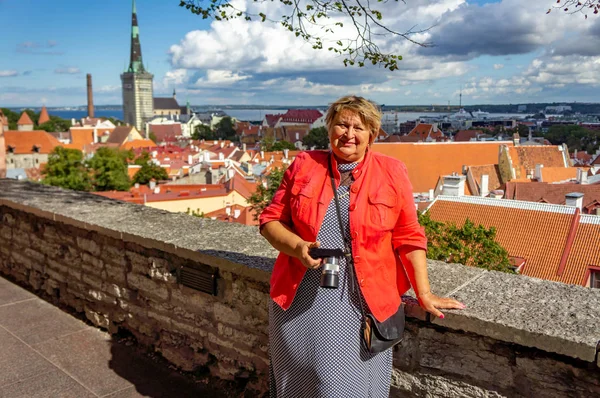 En mogen fyllig kvinna i rött promenader i ett gammalt slott, ler en — Stockfoto