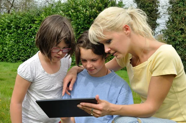Familie sitzt auf dem Rasen und nutzt digitales Tablet — Stockfoto