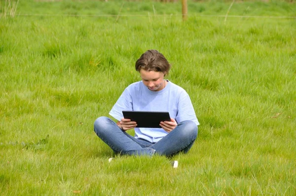 芝生の上に座って、デジタル タブレットを使用しての女の子 — ストック写真