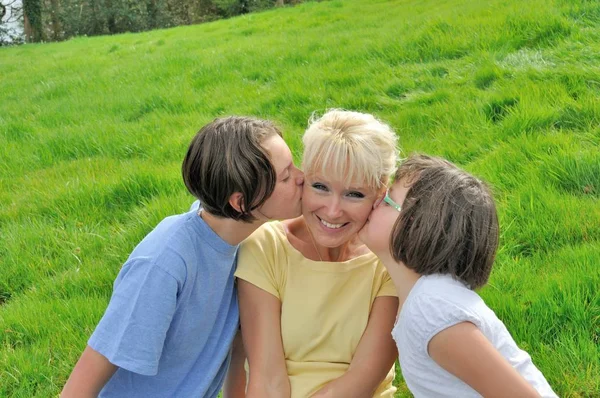 A mother smiles as she receives a kiss on the cheek from her you — Stock Photo, Image