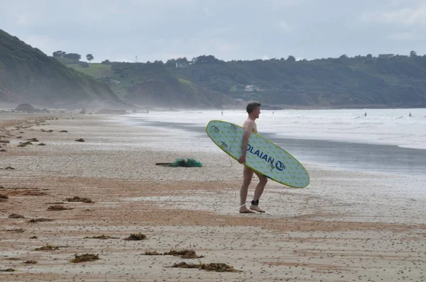 Erquy, Francja -20 sierpnia 2018: Mężczyzna z deską surfingową na plaży — Zdjęcie stockowe