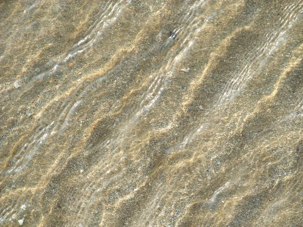Water flowing over sand forming pattern — 스톡 사진