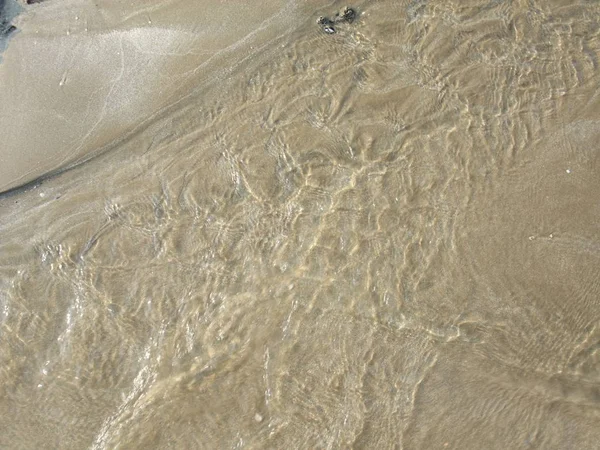 Acqua che scorre sopra sabbia formando modello — Foto Stock