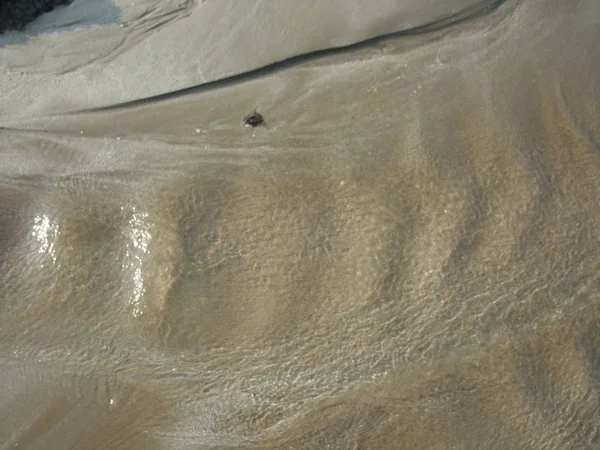 Woda przepływająca przez wzór formujący piasek — Zdjęcie stockowe