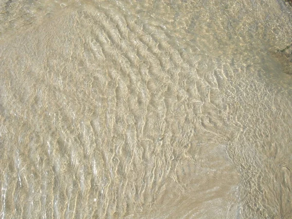 Vatten som rinner över sandformningsmönster — Stockfoto