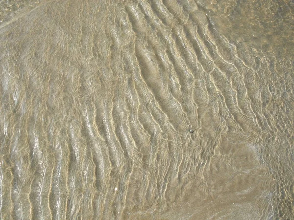 Acqua che scorre sopra sabbia formando modello — Foto Stock