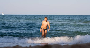 Bir genç denizden sahile çıkar..