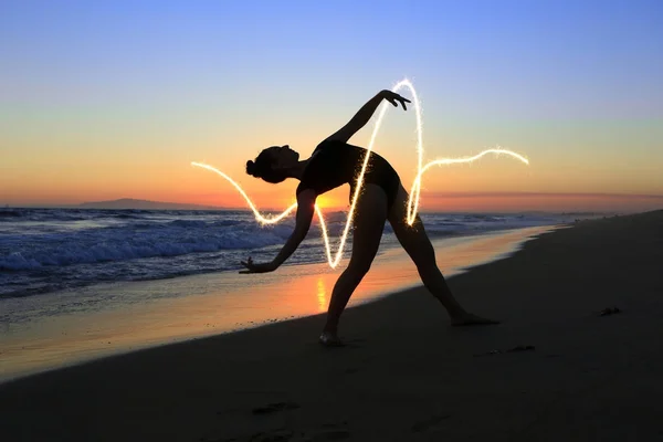 Geschoolde jonge danser op het strand tijdens zonsondergang — Stockfoto