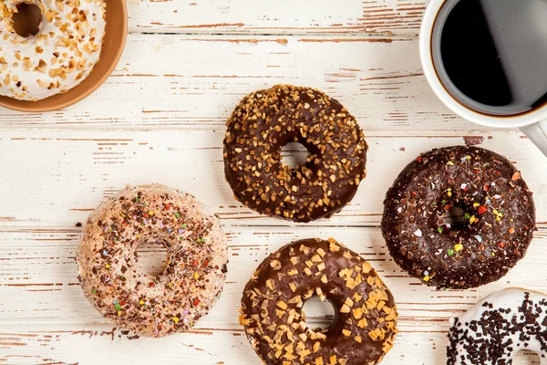 Donuts saborosos no fundo de madeira branca — Fotografia de Stock