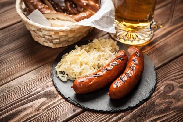 Çubuk kraker, bratwurst ve ahşap masa üzerinde lahana turşusu