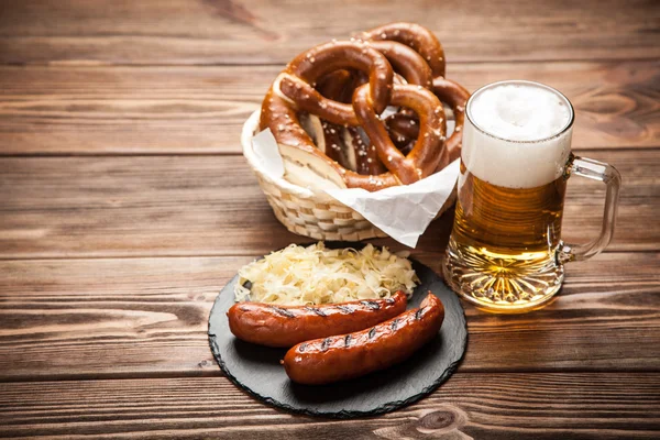 Pretzels, bratwurst and sauerkraut on wooden table — Stock Image Pretzels, bratwurst and sauerkraut on wooden table Stock Image