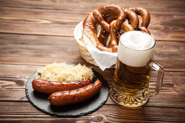 Pretzels, bratwurst and sauerkraut on wooden table — Stock Photo, Image