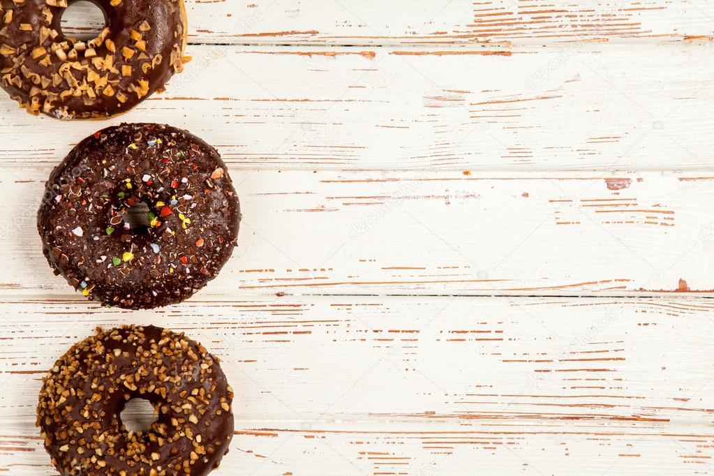 Tasty donuts on white wood background