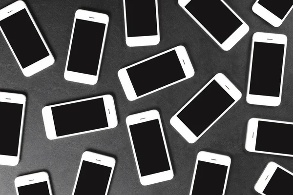 Sötét felszínen fekvő fehér okostelefonok — Stock Fotó