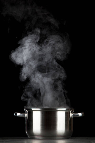 Steaming pot on black background