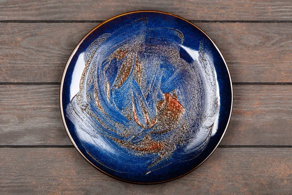 Blue plate na brązowy drewniany stół — Zdjęcie stockowe