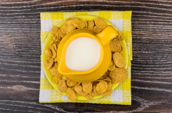 Yellow jug milk in saucer with corn flakes checkered napkin