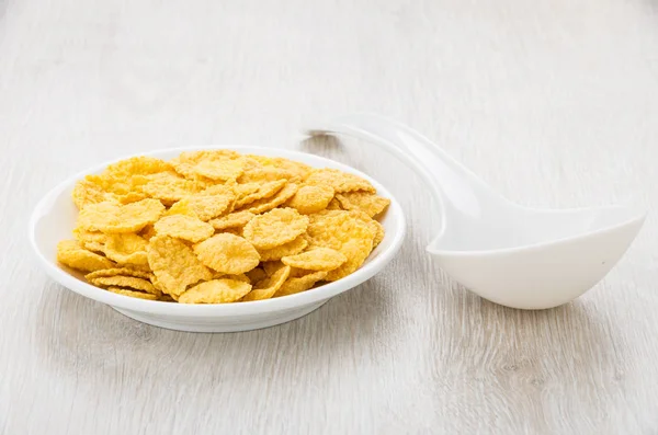 Saucer with corn flakes and white plastic spoon on table