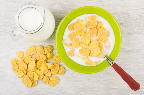 Corn flakes with milk in green bowl, jug