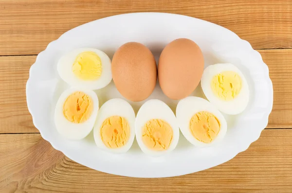 Oval dish with boiled eggs on wooden table