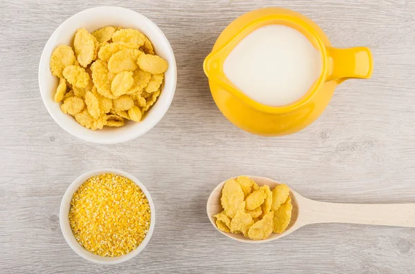 Bowls with corn grits and cornflakes, jug milk and spoon
