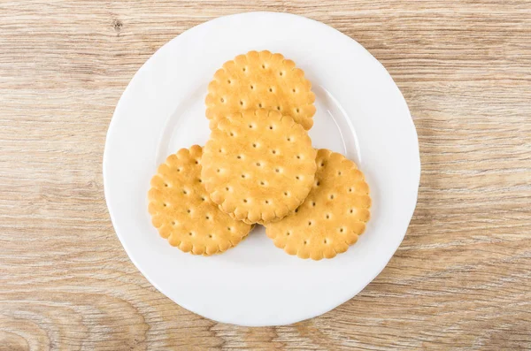 Round cookies in white plate on wooden table
