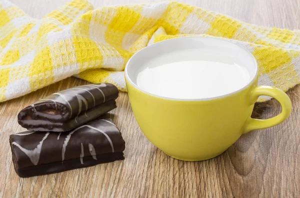 Chocolate swiss rolls, yellow napkin and cup of milk