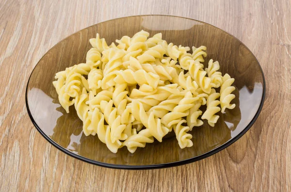 Boiled pasta fusilli in brown plate on table