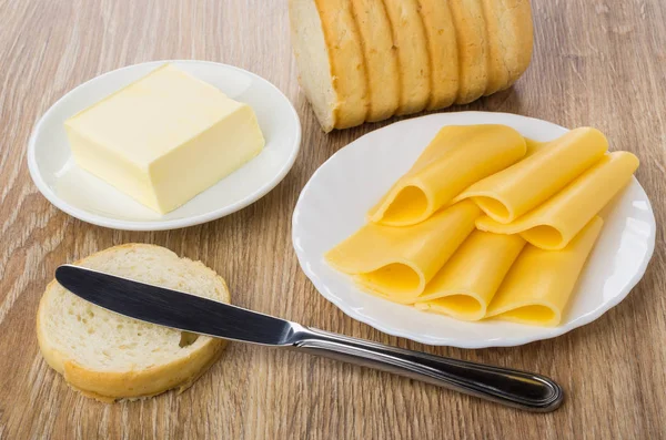Slices of cheese, bread, piece of butter in saucer, knife
