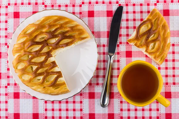Piece of pie with cottage cheese, cup of tea, knife