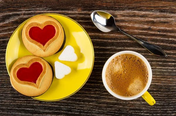 Cookies with jam hearts, sugar in saucer, spoon, cup with espres