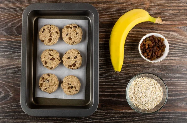 Raw cookies from oat flakes, banana, raisin on oven-tray, banana