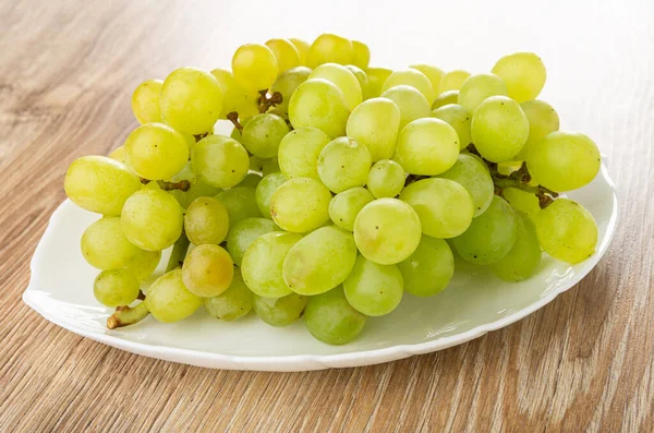 Bunch of ripe grape in white dish on wooden table