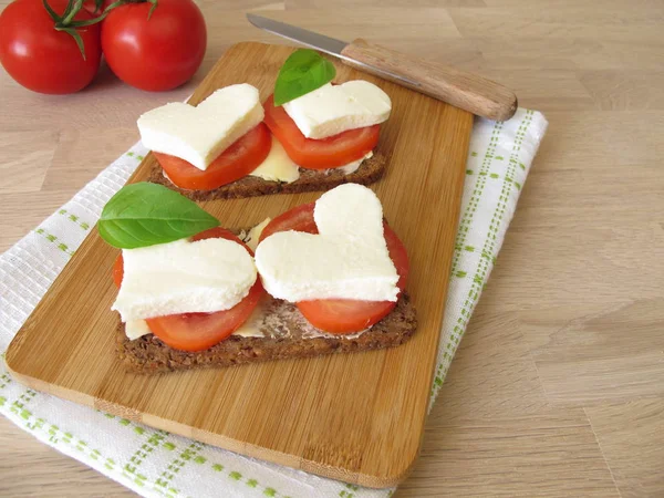 Linseeds bread with tomatoes, mozzarella heart and basil — Stock Photo, Image