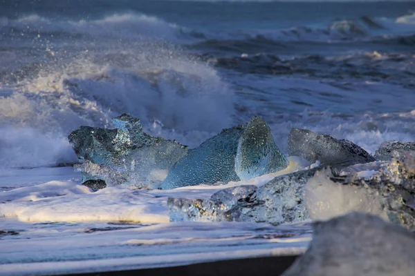 冰岛的一个海滩上 冰川湖畔融化的冰河中涌现出的蓝色冰块 海浪冲刷着它们 图库照片