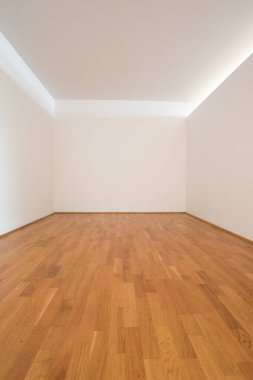 Ahşap zemin ve beyaz duvarları olan boş bir oda.