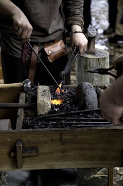 Demirci demircisinde bir demir parçasını ısıtıyor. Demir parlıyor, sıcak bir şeye dönüşmeye hazır..