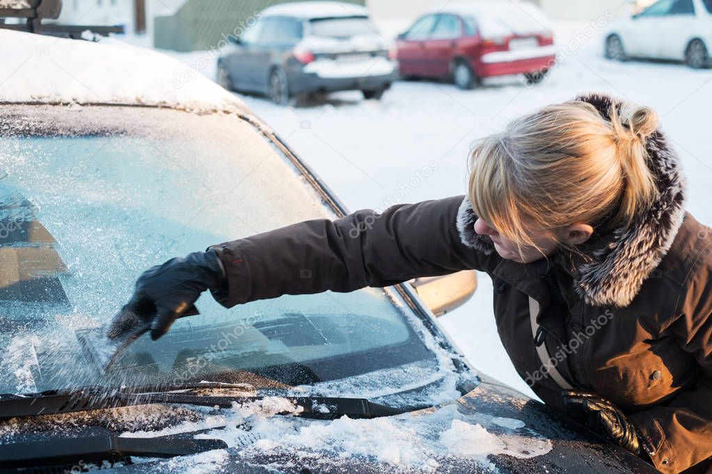 Woman scraping ice from car window