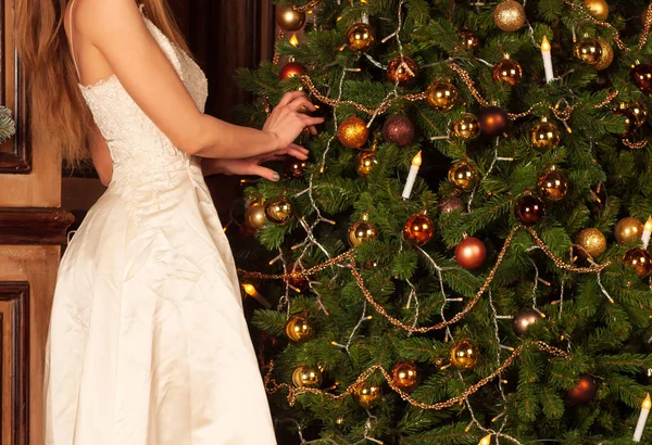 Woman in white dress decorates christmas tree — Stock Photo, Image