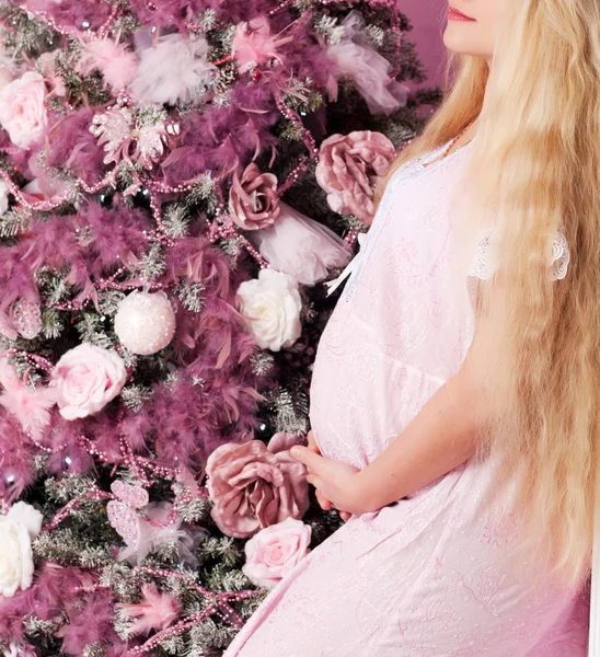 Zwangere vrouw in de buurt van een versierde kerstboom — Stockfoto