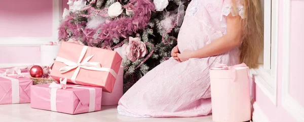 Femme enceinte avec un cadeau près d'un arbre de Noël décoré — Photo