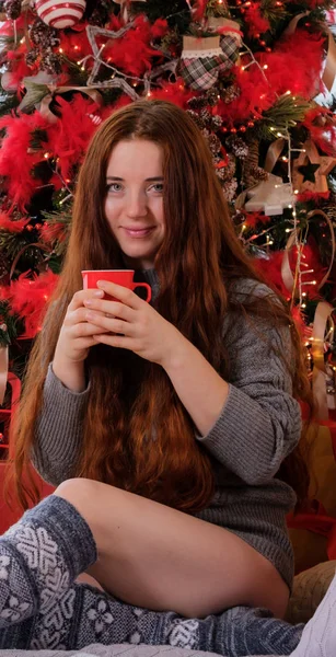 Frau mit einer Tasse in der Hand und im warmen Pullover sitzt neben — Stockfoto