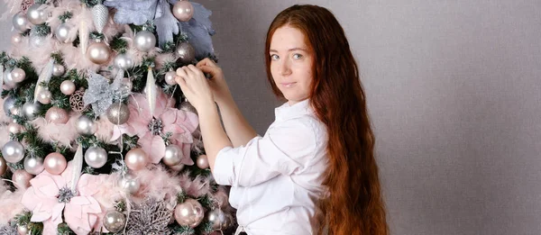 Wanita dengan rambut merah panjang menghias pohon Natal — Stok Foto