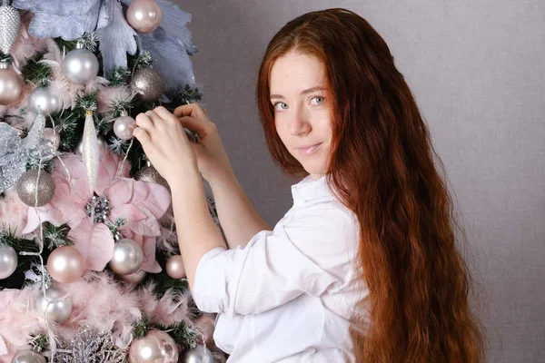 Femme aux longs cheveux roux décore un arbre de Noël — Photo