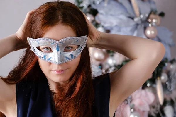 Woman with long red hair with a masquerade mask on her face near — Stock Photo, Image