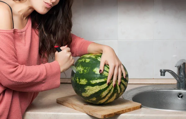 Woman in the kitchen cuts watermelon — Stock Photo, Image