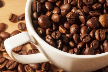 Masada beyaz kahve fincanı ve kavrulmuş kahve çekirdekleri.