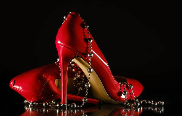 Patent leather shiny female red stilettos and beads on a black b — 图库照片